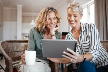 We have to watch these videos. Shot of two female friends drinking coffee while using a digital tablet.