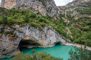 Obraz premium Deep turquoise river at the bottom of a vertical canyon with people kayaking.
