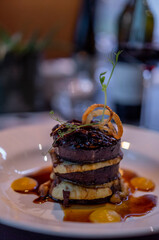 Blutwurst mit Zwiebeln angerichtet auf eleganten Teller mit Weinbegleitung