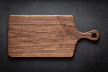 Black walnut handmade wooden chopping board. Handmade black walnut wooden cutting board on dark tone texture background.