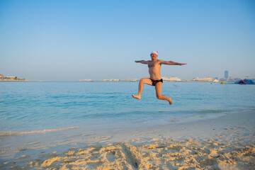 a man jumping on the beach wearing a santa hat