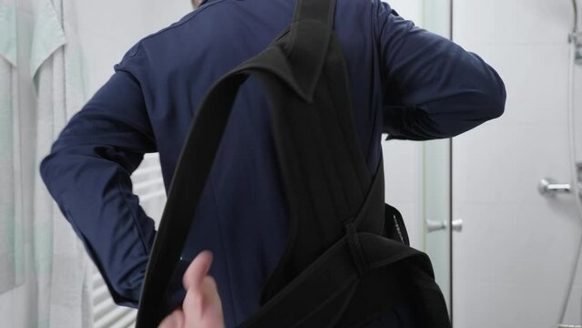 Headless businessman in bathroom put on orthopedic posture belt over elegant blue shirt 4K