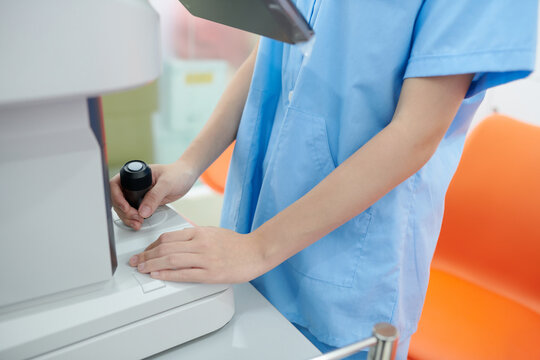 Cropped Image Of Ophthalmic Nurse In Scrubs Using Modern Equipment When Checking Eyesight Of Patient In Clinic