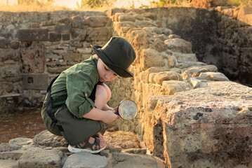 Boy archaeologist in khaki clothes studying the ruins of an ancient city. Diverse, non-traditional...