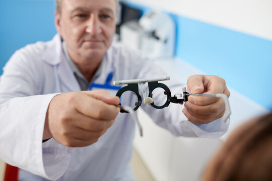 Optometrist asking patient to wear adjustable trial lens frame during medical examination, selective focus