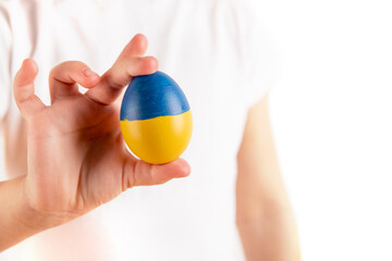 Little girl holding easter eggs on blue and yellow background.