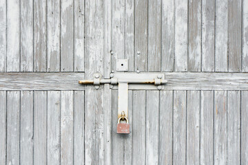 Wooden door background. Garage door texture. Abandoned locked gate. Metal padlock with peeling paint.