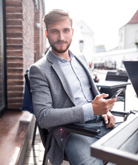 businessman with a smartphone sitting at a table in a street cafe