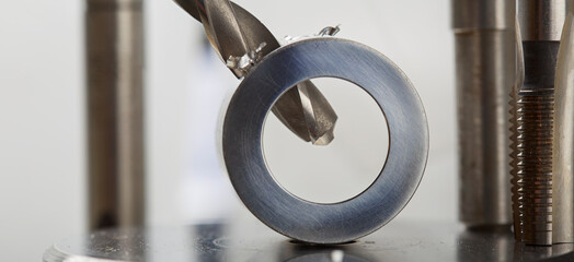metal drill bit make holes in aluminium pipe on industrial drilling machine. Metal work industry.