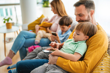 Parents with children playing games, using mobile apps on phone at home