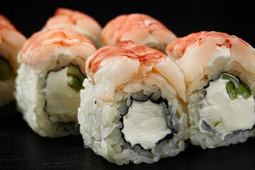 Sushi rolls Philadelphia with snow crab, cream cheese, cucumber, sesame seeds isolateed on black background. Japanese oriental cuisine
