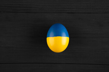 easter egg with the flag of Ukraine on a wooden background.