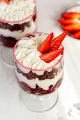 Chocolate brownie trifle with cream cheese and strawberries. Dessert in a glass. Close-up.