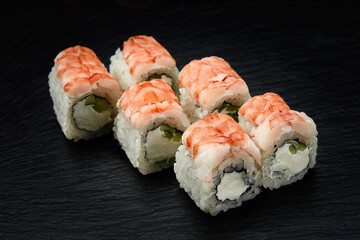 Sushi rolls Philadelphia with snow crab, cream cheese, cucumber, sesame seeds isolateed on black background. Japanese oriental cuisine