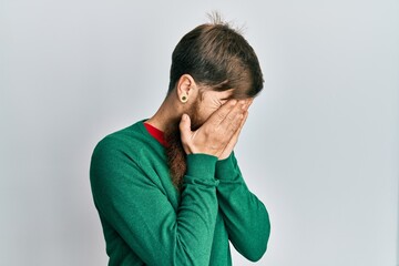 Redhead man with long beard wearing casual clothes with sad expression covering face with hands while crying. depression concept.