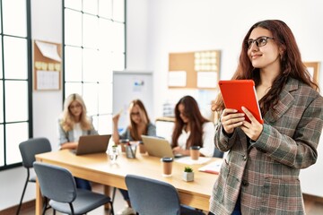 Young businesswoman smiling happy using touchpad while partners work at the office.