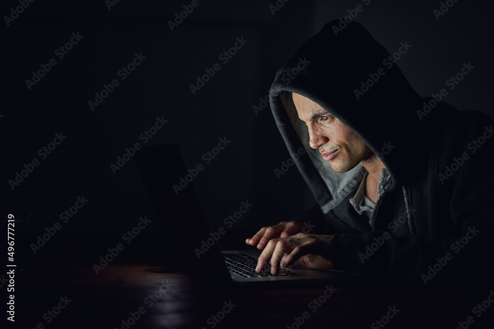 Aufkleber protect yourself before its too late. shot of a hooded computer hacker using a laptop in the dark.