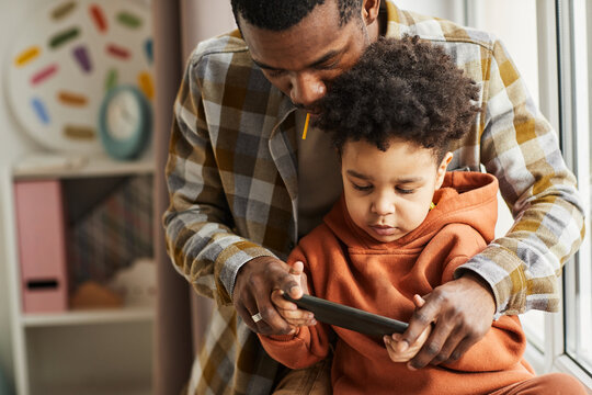 Waist up portrait of African American father and little boy using smartphone together and watching cartoons online, copy space - Powered by Adobe