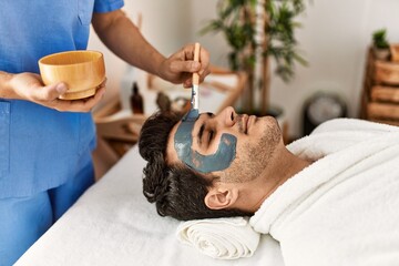 Man reciving facial treatment at beauty center.