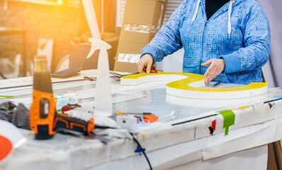 Applying colored yellow membrane to a surface of plastic 3d letter of signboard. worker's hands close up