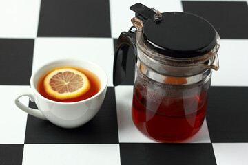 Tea with lemon and a teapot on a chessboard.