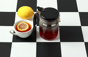 Tea with lemon and a teapot on a chessboard.