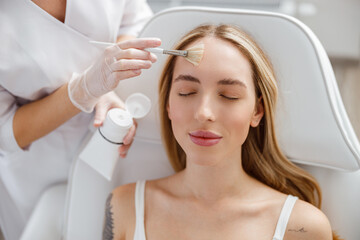 Woman receiving facial skincare treatment in cosmetology clinic