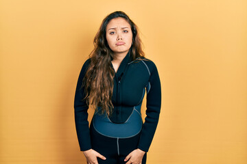 Young hispanic girl wearing diver neoprene uniform depressed and worry for distress, crying angry and afraid. sad expression.