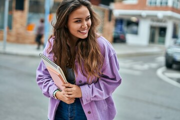 Young hispanic student woman smiling happy standing at the city.