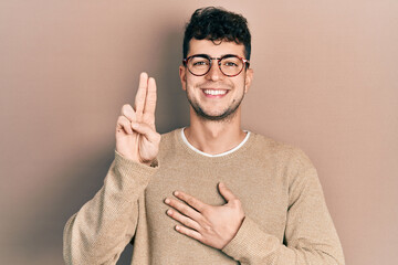 Young hispanic man wearing casual clothes and glasses smiling swearing with hand on chest and...
