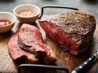 Barbecue Grilled rump cap or brazilian picanha beef meat steak in a wooden tray. Grey background