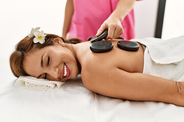 Young latin woman having back massage session using hot stones