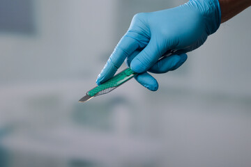 Ready to cut - Doctor's hand with a new disposable scalpel - obrazy, fototapety, plakaty