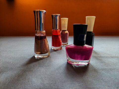 Group of five different nail polish or nail paint color bottles kept on table under natural light. pink, red, black shiny brown, light brown color shades of nail paint. Picture captured at Bangalore.