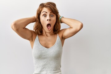 Beautiful caucasian woman standing over isolated background crazy and scared with hands on head, afraid and surprised of shock with open mouth