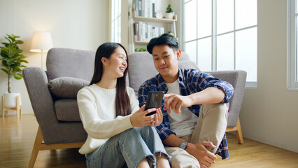 Asian couple man and woman using mobile phone, spend time together at home, Asian couple family...