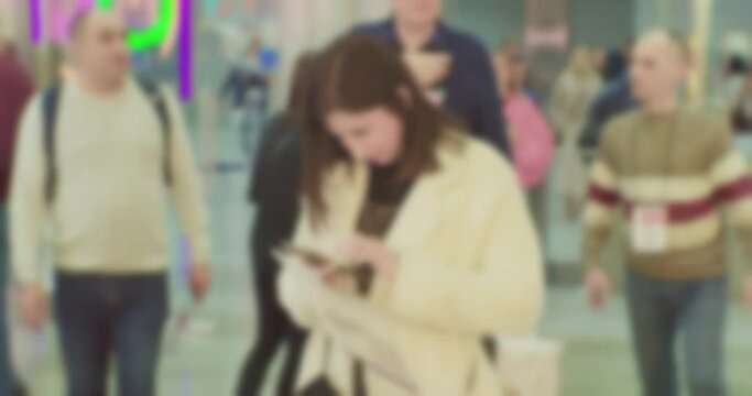 blurry defocused video.unrecognizable woman talking on smartphone in busy crowded place