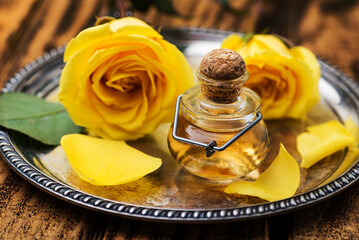 yellow rose flower and  bottle essential oil or rose water with rose petals