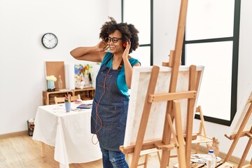 Young african american woman listening to music and dancing at art studio