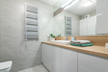 Jasna łazienka z dużym lustrem i umywlką, pojemnymi szafkami oraz kabiną prysznicową