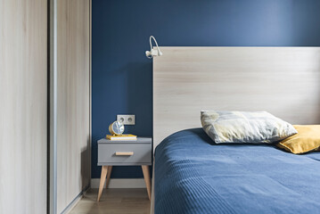 Niebieska sypialnia z dużym łózkiem, pojemnymi szafami na ubrania oraz akcesoriami wnętrzarskimi - obrazy, fototapety, plakaty
