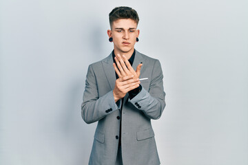 Young caucasian boy with ears dilation wearing business jacket suffering pain on hands and fingers, arthritis inflammation