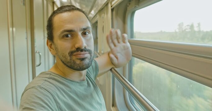 A young attractive man Takes a selfie on a train ride. Welcome hand sign.