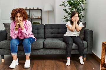 Mature mother and down syndrome daughter looking upset and angry after discussion at home
