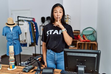 Young hispanic woman working as staff at retail boutique asking to be quiet with finger on lips. silence and secret concept.