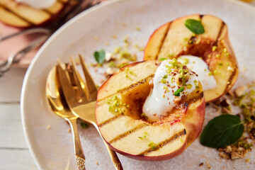 Tasty grilled peaches with yogurt and pistachios on plate
