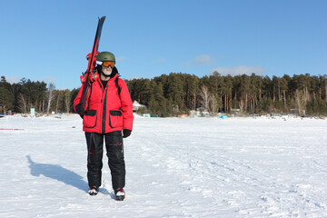 Man in a red jacket with alpine skis going to training in winter