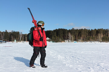 Man in a red jacket with a backpack and alpine skis going to training in winter