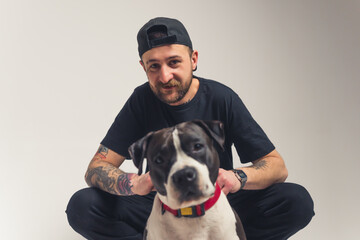 Adorable bond between pedigree dog and its owner. European bearded tattooed man in black clothes...
