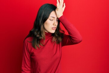 Young brunette woman wearing turtleneck sweater surprised with hand on head for mistake, remember error. forgot, bad memory concept.